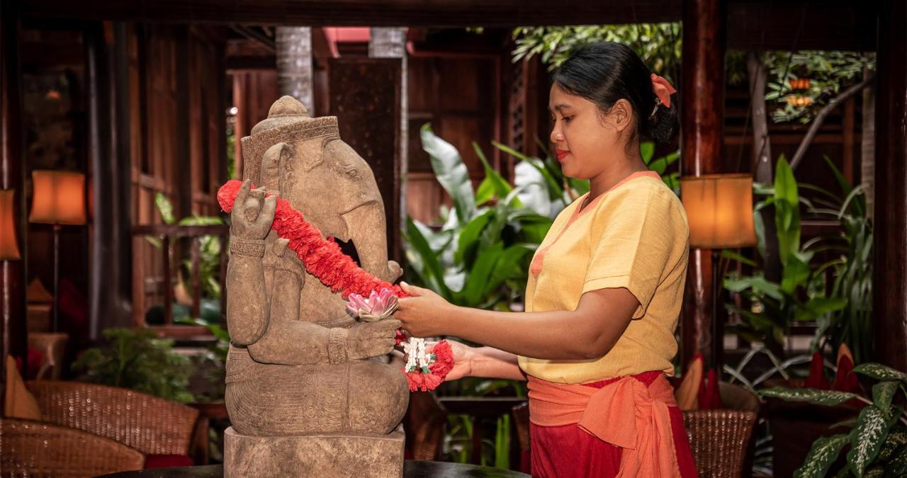 Angkor Village Hotel - Small Luxury Hotels Of The World Сиемрип Экстерьер фото A woman in Thailand, wearing traditional Thai clothing, garlands a statue of the Hindu god Ganesha.